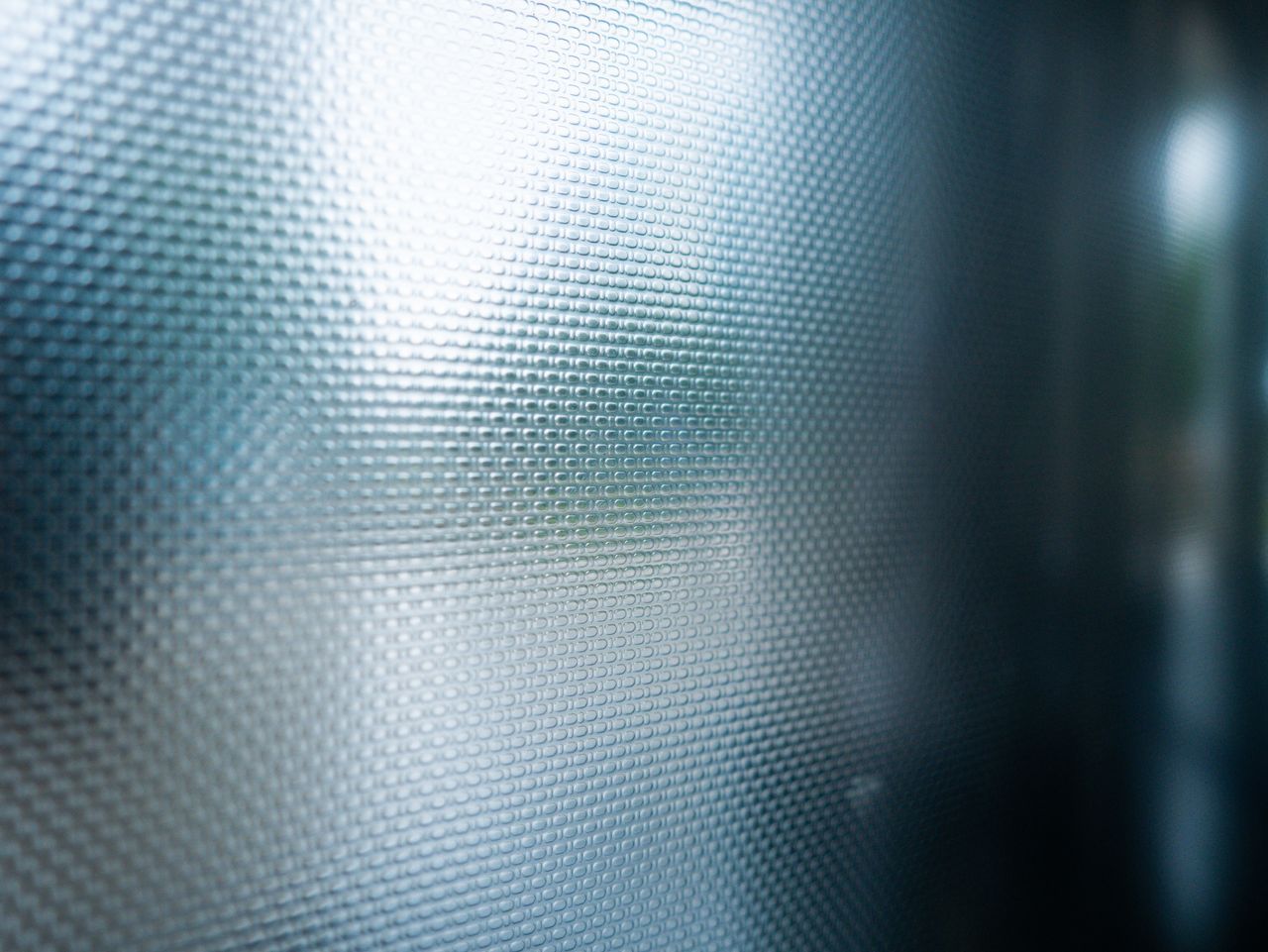 Detailed close-up of a textured smoked glass panel with a soft light reflection.